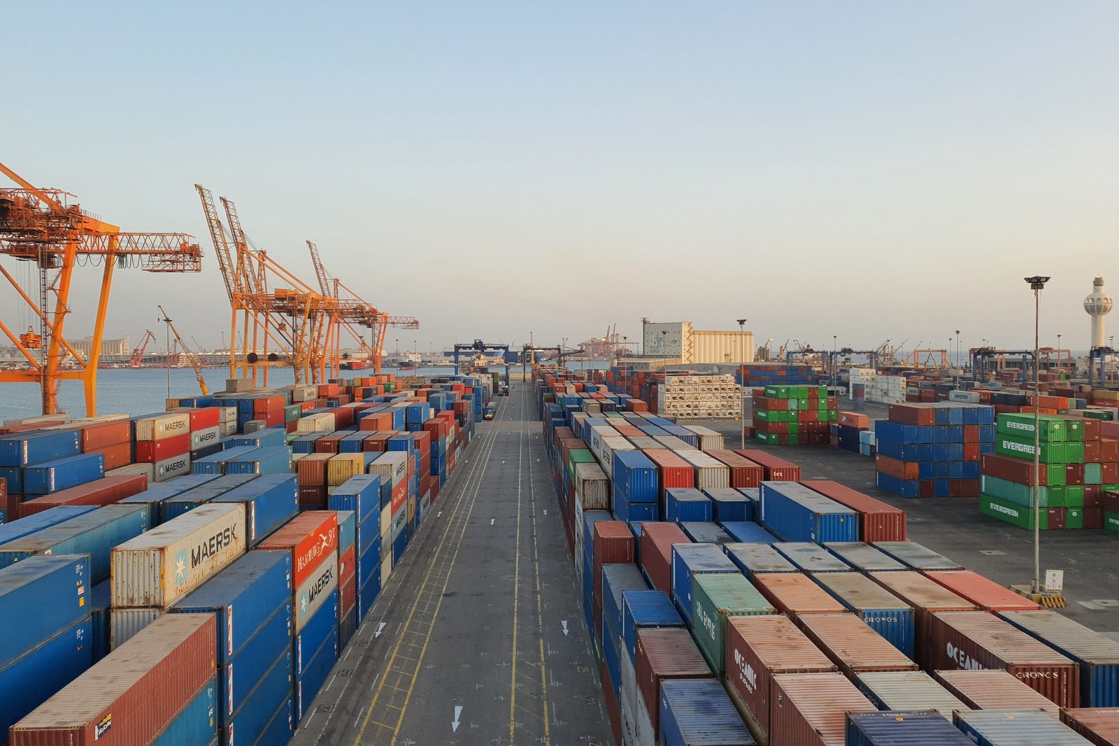 Shipping containers stacked several tiers high in rows across a port yard